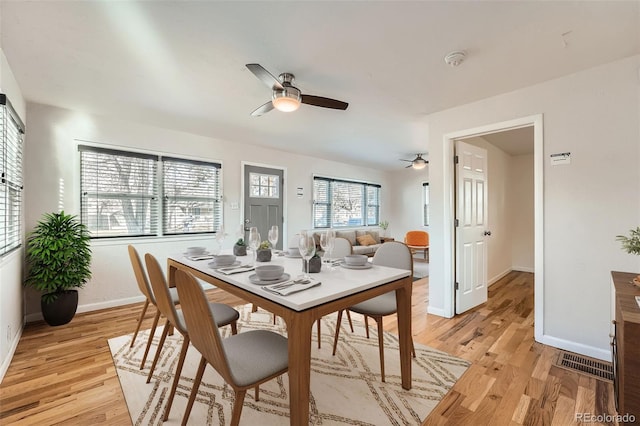 dining room with light wood-style flooring, visible vents, a ceiling fan, and baseboards