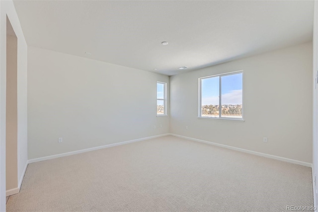 unfurnished room featuring light colored carpet and baseboards