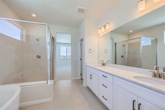 full bathroom featuring a stall shower, tile patterned floors, double vanity, a freestanding bath, and recessed lighting