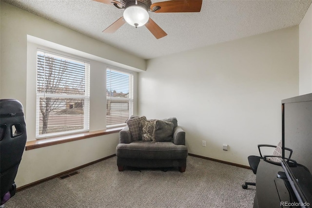 carpeted home office with ceiling fan, baseboards, visible vents, and a textured ceiling