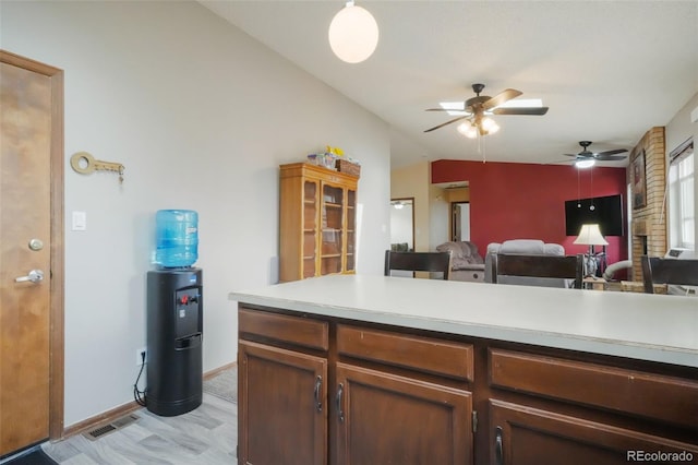 kitchen with visible vents, open floor plan, baseboards, light countertops, and lofted ceiling