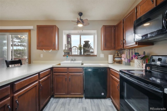 kitchen featuring a wealth of natural light, black appliances, light countertops, and a sink