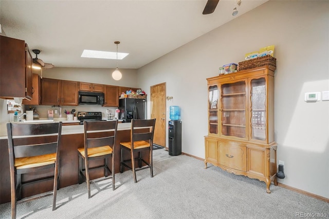 kitchen with lofted ceiling with skylight, light carpet, black appliances, a kitchen breakfast bar, and a peninsula