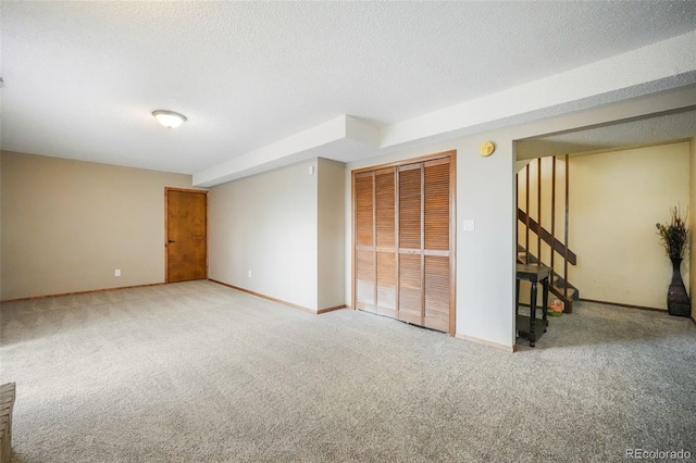 carpeted spare room featuring a textured ceiling and baseboards