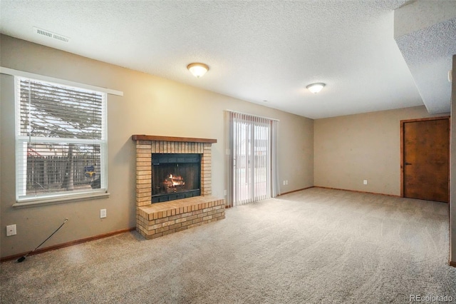 unfurnished living room with visible vents, carpet floors, a textured ceiling, and a brick fireplace