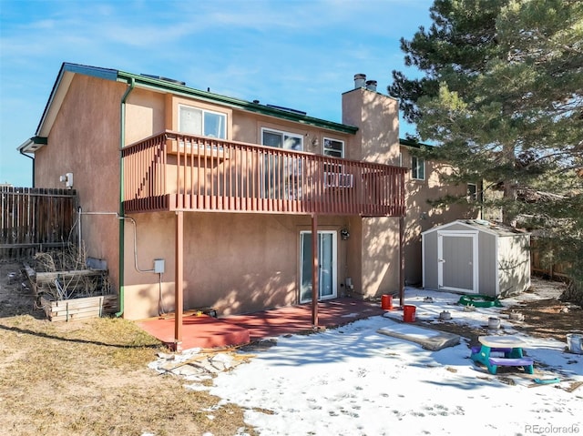 back of property with a chimney, stucco siding, a storage unit, and an outdoor structure