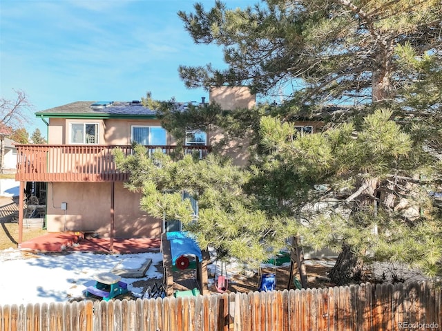 back of property featuring stucco siding, a deck, and fence