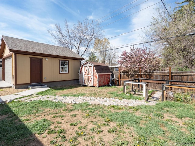 fenced backyard with an outbuilding, a storage shed, and a garage