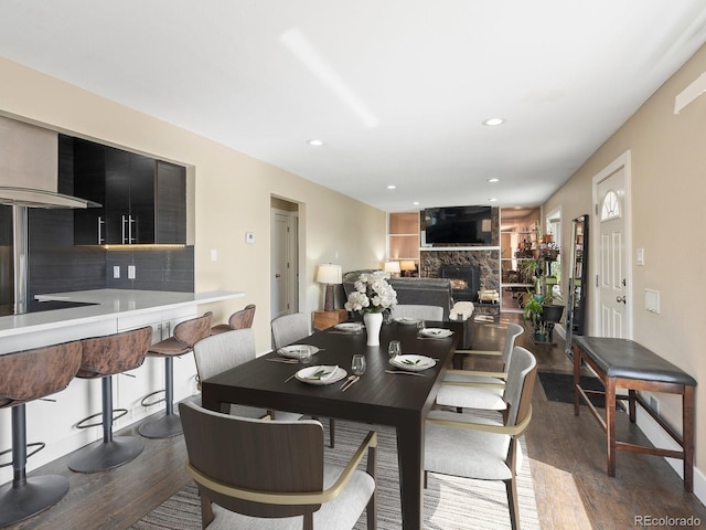 dining space with a fireplace, dark wood-style flooring, and recessed lighting