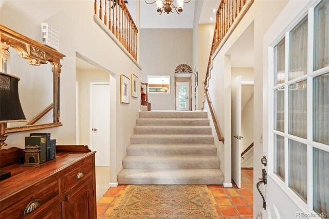 tiled foyer entrance featuring an inviting chandelier and a towering ceiling