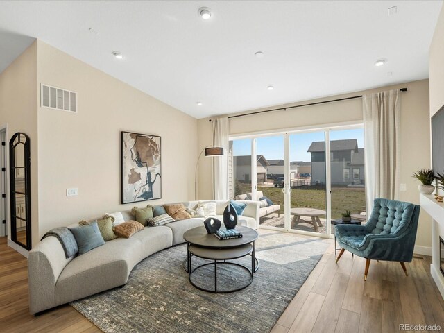 living area featuring recessed lighting, visible vents, wood finished floors, and vaulted ceiling