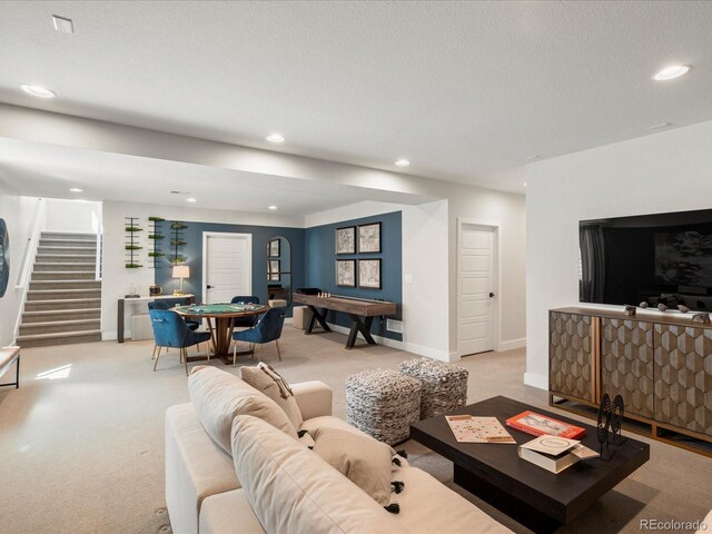 living room with recessed lighting, stairs, baseboards, and light colored carpet