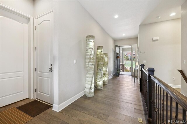 corridor featuring hardwood / wood-style floors, baseboards, an upstairs landing, and recessed lighting
