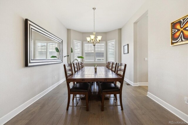 dining area featuring a chandelier, dark wood finished floors, and baseboards