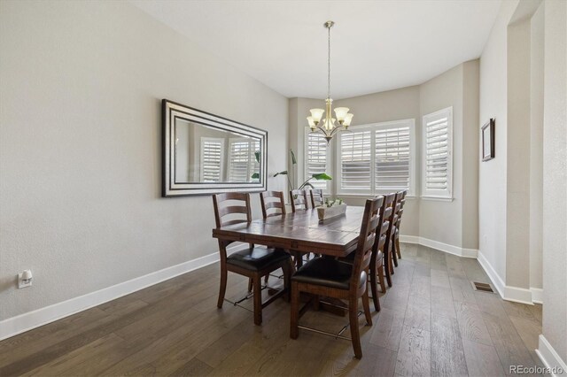 dining room with dark wood-type flooring, a chandelier, and baseboards