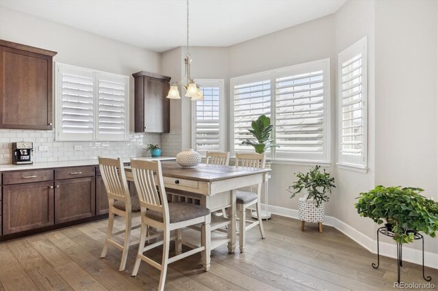 dining area with light wood-type flooring, a chandelier, and baseboards