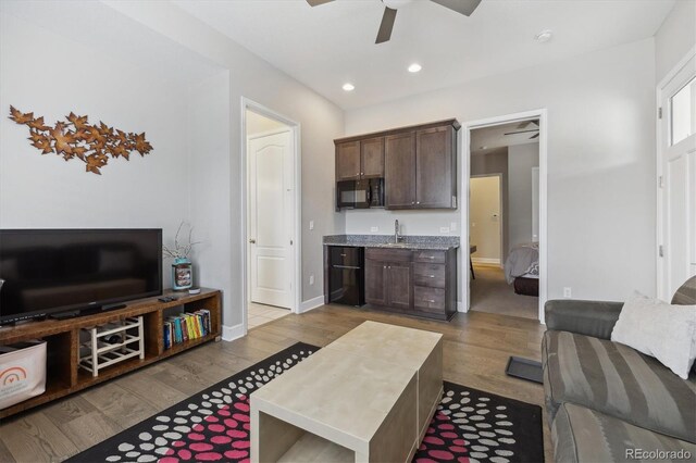 living area featuring ceiling fan, wood finished floors, bar with sink, recessed lighting, and baseboards