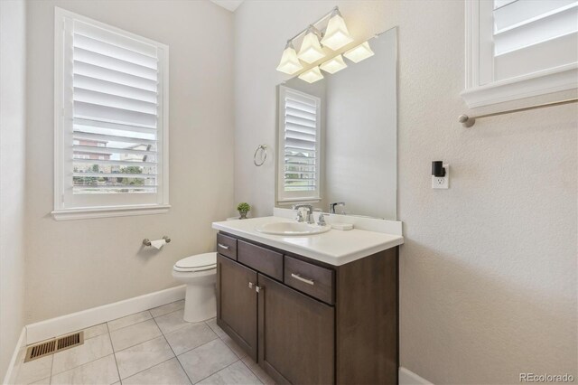 bathroom featuring plenty of natural light, vanity, baseboards, and toilet
