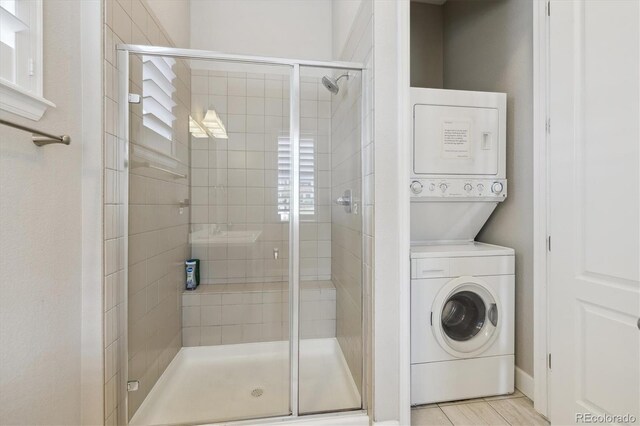bathroom featuring stacked washer and clothes dryer and a shower stall