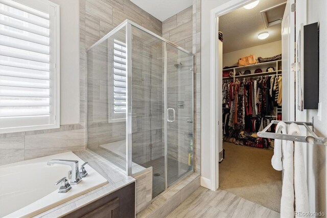 bathroom with a stall shower, a walk in closet, and a bath