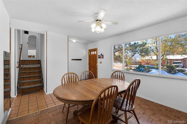 dining area featuring ceiling fan, dark parquet flooring, and a textured ceiling