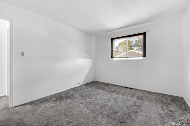 carpeted empty room featuring a textured ceiling