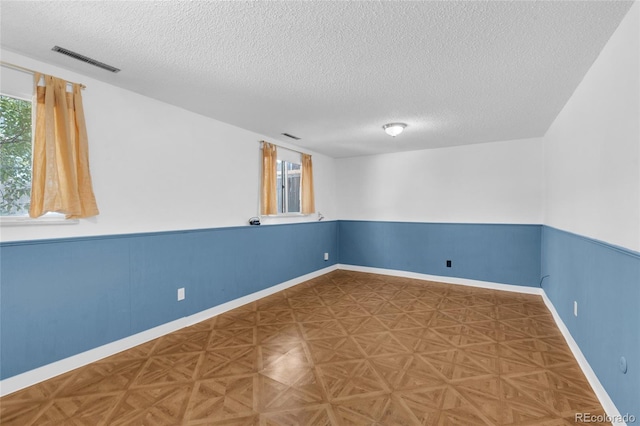 spare room with parquet floors and a textured ceiling