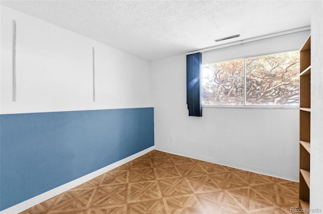 spare room with parquet flooring and a textured ceiling