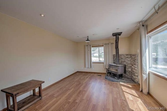 unfurnished living room featuring a wood stove and light wood-type flooring