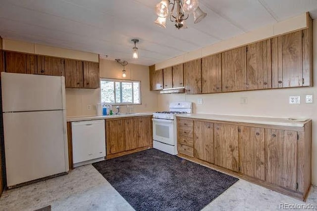 kitchen with sink, an inviting chandelier, and white appliances