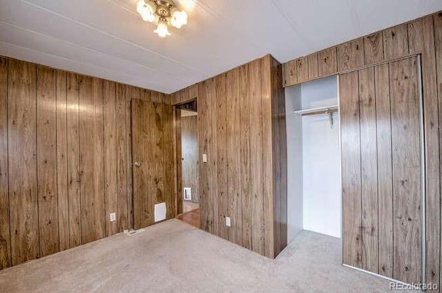 unfurnished bedroom with wood walls, a closet, and carpet floors