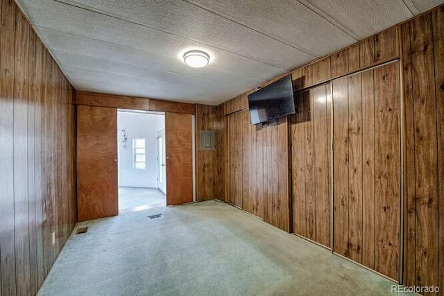 carpeted spare room with wood walls