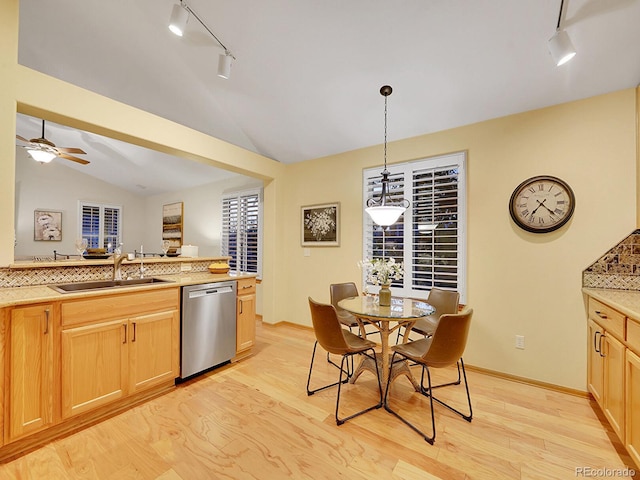 kitchen with dishwasher, sink, decorative light fixtures, lofted ceiling, and light wood-type flooring