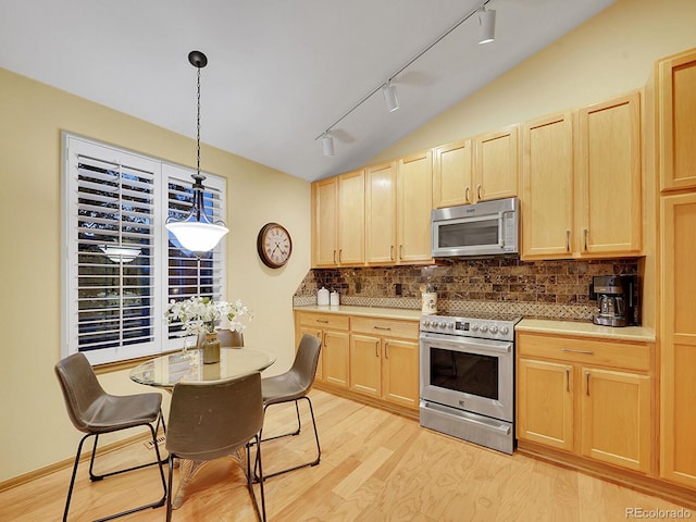 kitchen with decorative light fixtures, light brown cabinetry, stainless steel appliances, and light hardwood / wood-style floors