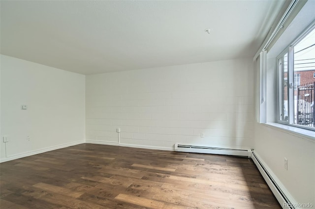 empty room with dark hardwood / wood-style flooring and a baseboard radiator