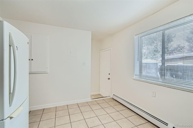 tiled spare room with a baseboard heating unit