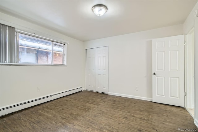 unfurnished bedroom with a closet, dark hardwood / wood-style floors, and a baseboard heating unit