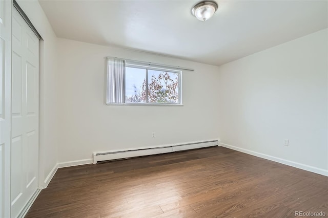 unfurnished bedroom featuring baseboard heating, dark hardwood / wood-style floors, and a closet