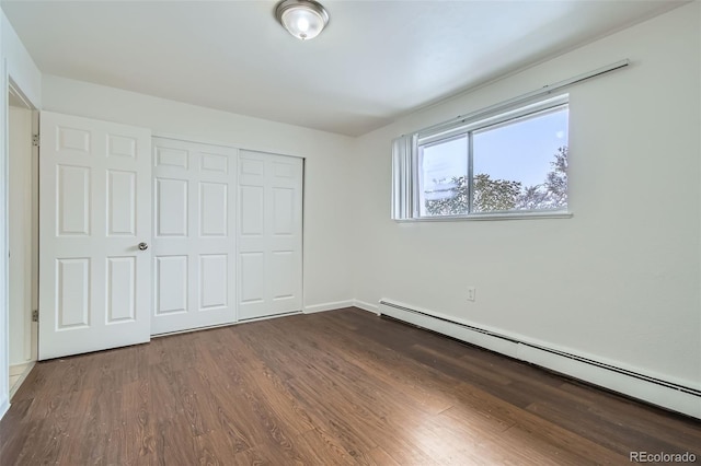 unfurnished bedroom featuring dark hardwood / wood-style flooring, a closet, and baseboard heating