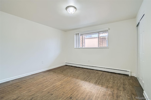 unfurnished bedroom featuring dark wood-type flooring, a closet, and a baseboard heating unit