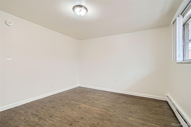 empty room with a baseboard heating unit and dark hardwood / wood-style flooring