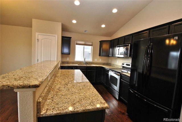 kitchen featuring appliances with stainless steel finishes, sink, lofted ceiling, light stone counters, and a kitchen island