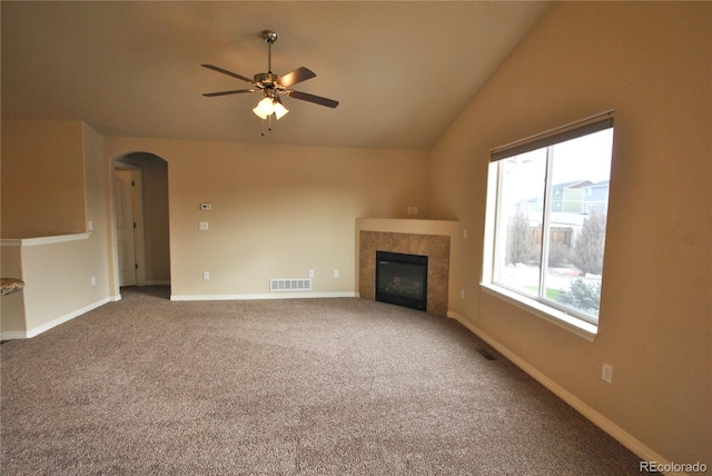 unfurnished living room featuring ceiling fan, a tile fireplace, carpet floors, and lofted ceiling