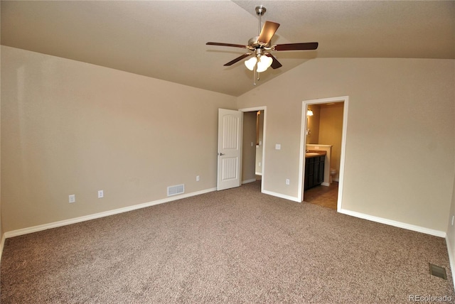 unfurnished bedroom with ceiling fan, dark colored carpet, ensuite bath, and lofted ceiling