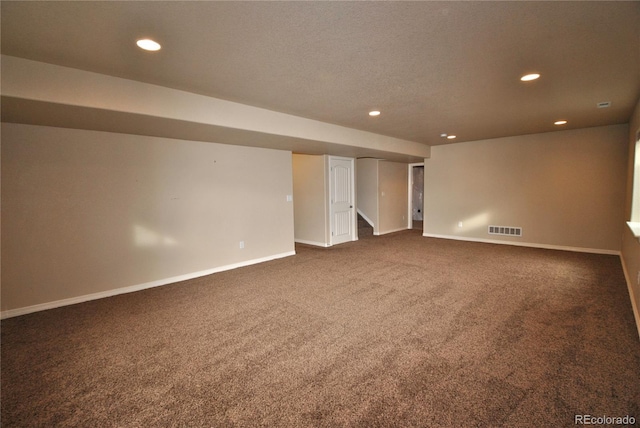 spare room featuring a textured ceiling and dark colored carpet