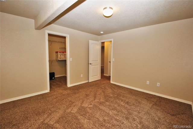 carpeted empty room with a textured ceiling and beam ceiling