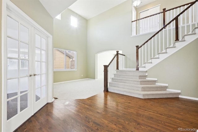 foyer entrance featuring dark hardwood / wood-style flooring, a towering ceiling, and french doors