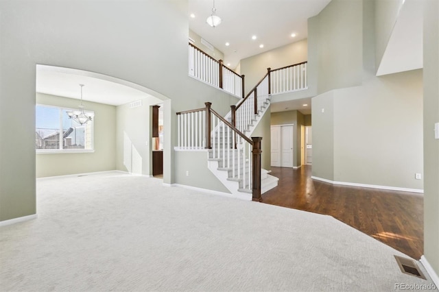 interior space with an inviting chandelier, a towering ceiling, and carpet