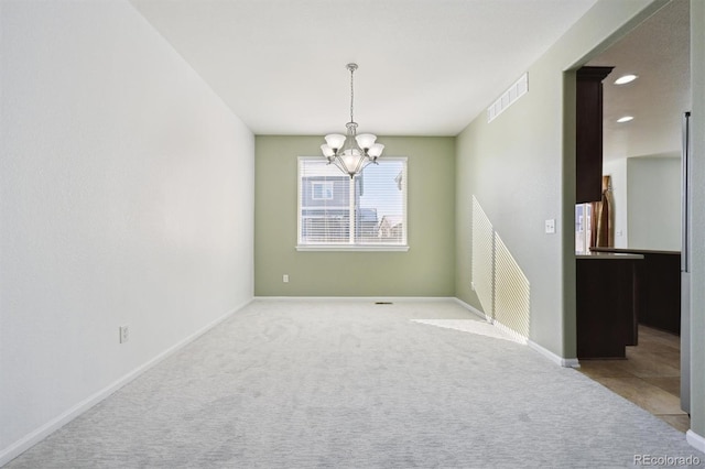 carpeted spare room with an inviting chandelier