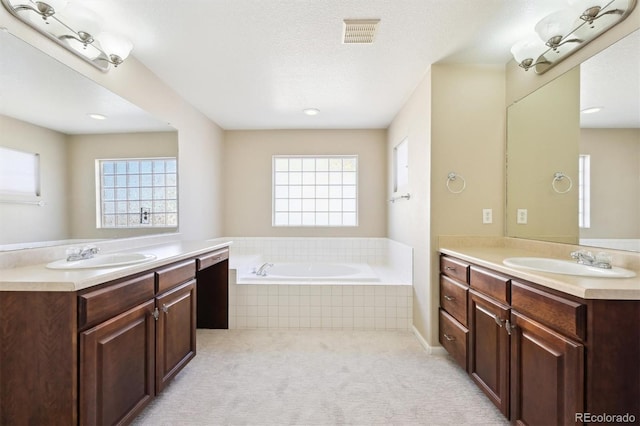 bathroom featuring vanity, tiled bath, and a textured ceiling